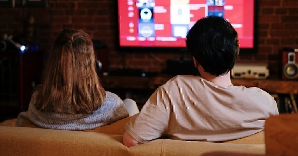 A couple sitting down to watch their favorite military-themed movie.