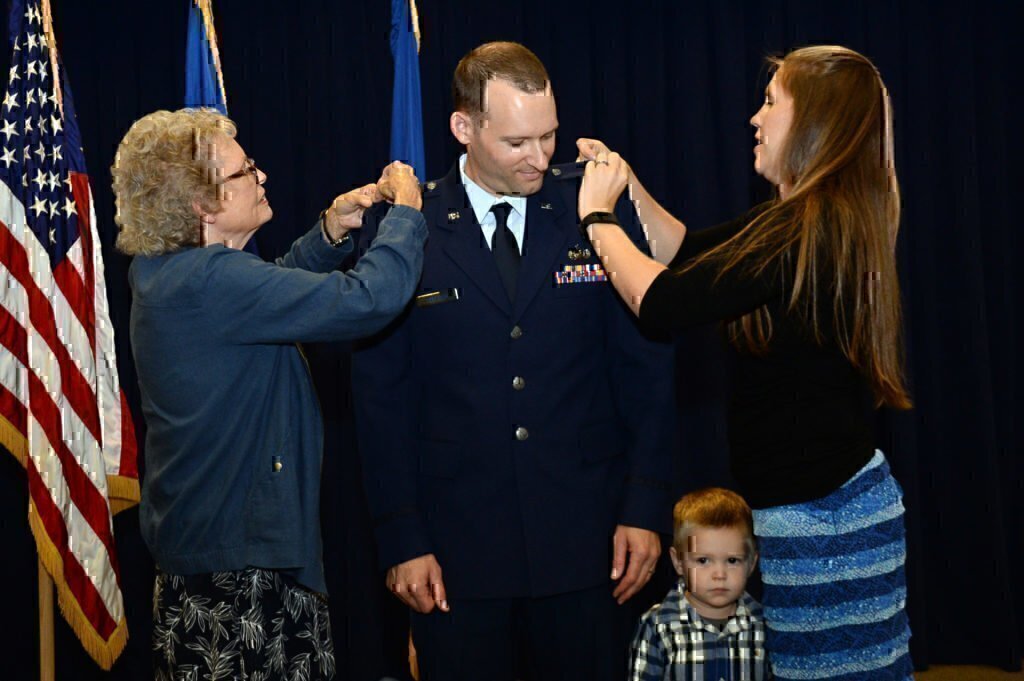 A wife helping to pin together her military husbands uniform.