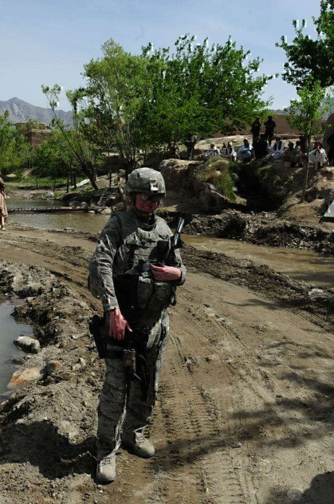 A female service-member smiling for the camera as she goes through her daily activities.