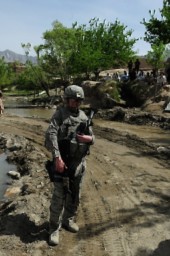 A female service-member smiling for the camera as she goes through her daily activities.