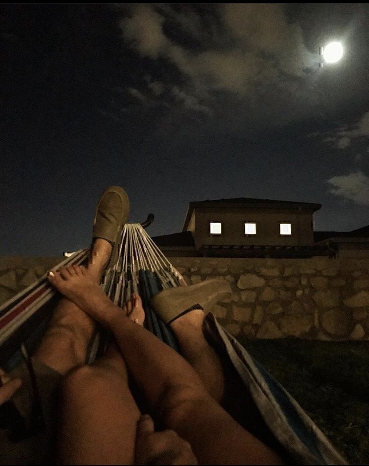 The legs of a couple laying on a hammock.