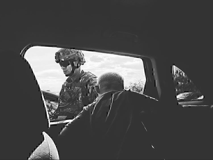 An officer talking with a young boy that is seated in a car.