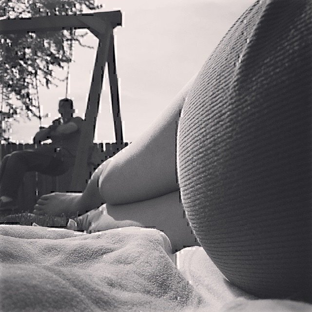 A laying down on the ground, photographing her legs and pregnant stomach.