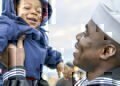 A Navy seamen lovingly picks up his smiling baby boy after coming home from deployment
