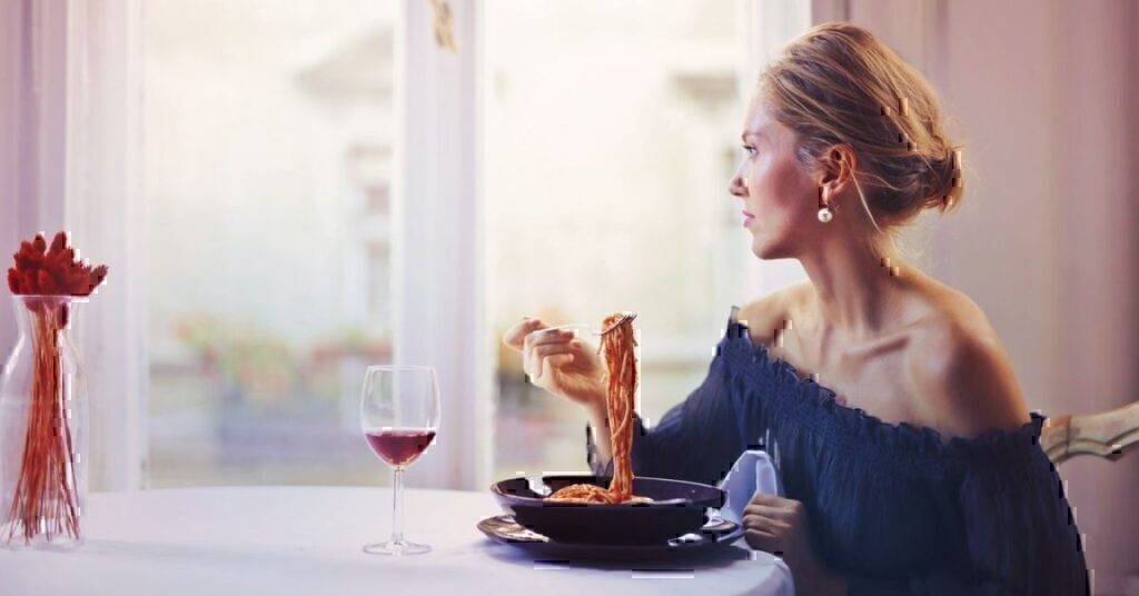 A women looking out of her window while eating her lunch alone.