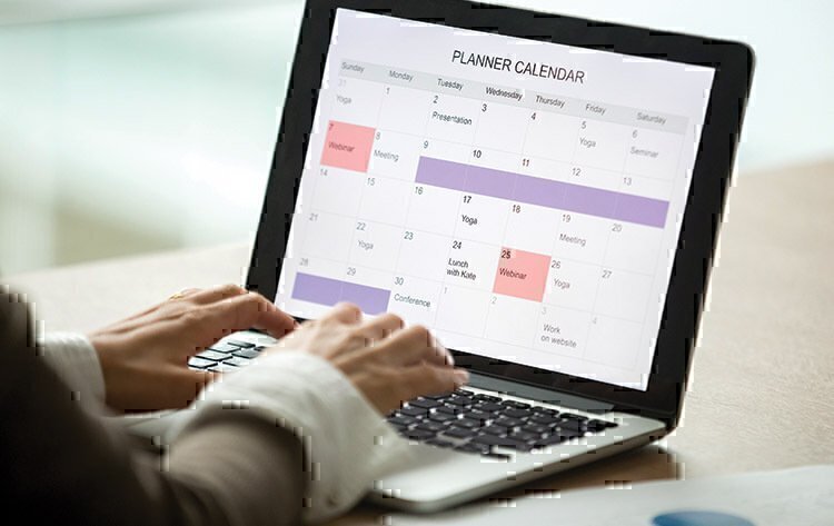 A women using her laptop to set up her calendar for her month.