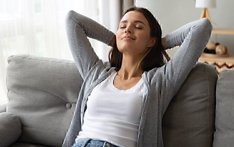 A women seated on a couch, relaxing.