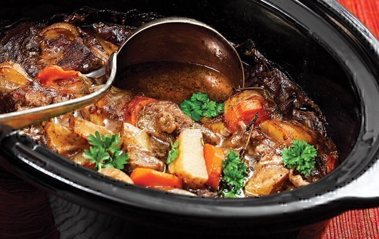 A beef stew being stirred up by a ladle.