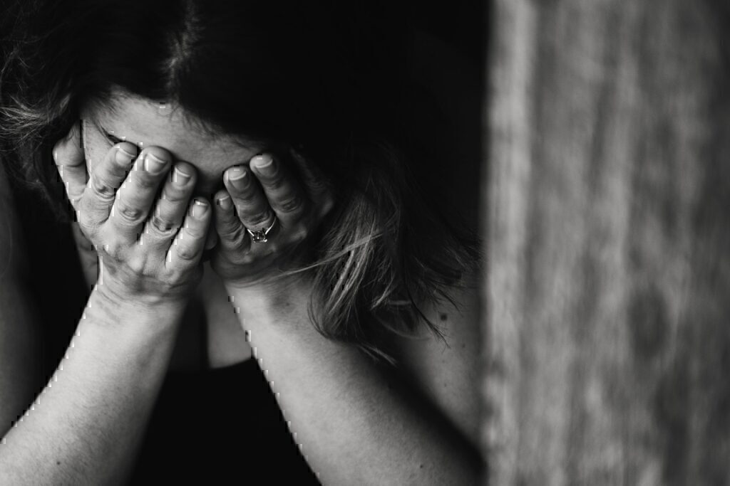 A women holding her face in her hands while sad.