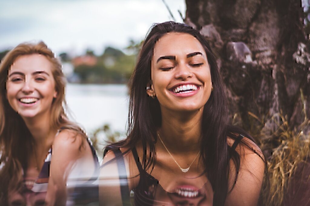 Two women sitting and smiling with each other.